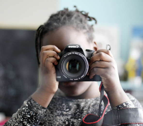 criança negra com máquina fotográfica