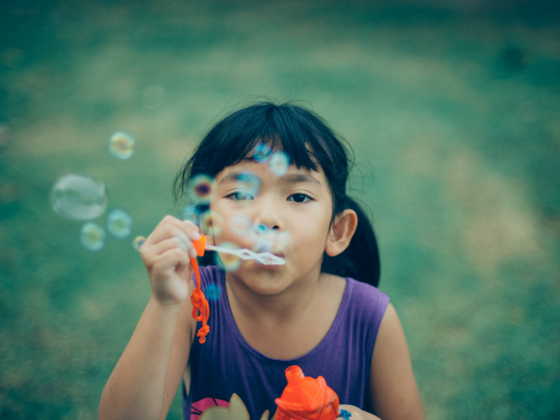 criança oriental fazendo bolhas de sabão