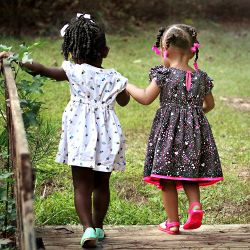 crianças negras de mãos dadas andando no jardim